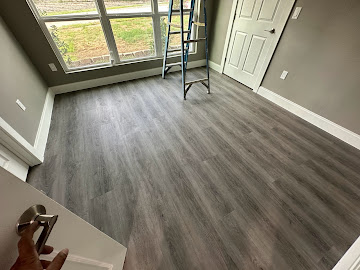 Living space with new grey plank flooring, trim work and interior door install