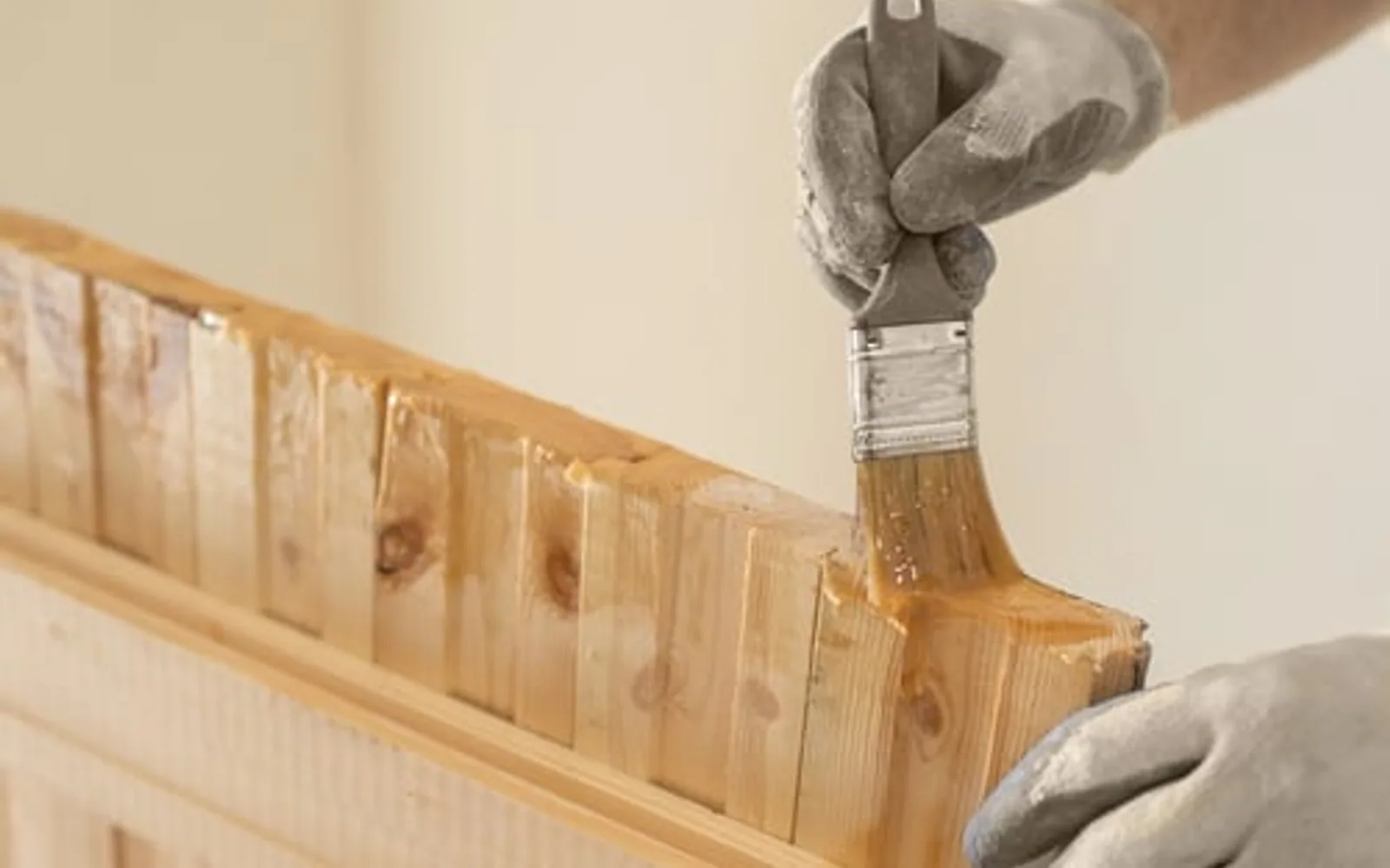 Craftsman brushing a fresh finish onto a wood cabinet face during a refinishing job